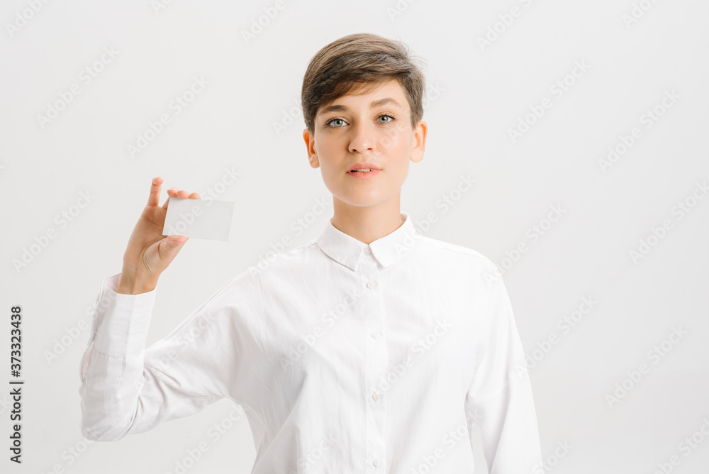 girl in a white office shirt holds out a business card. close portrait. girl in a white office shirt holds out a business card. close portrait.