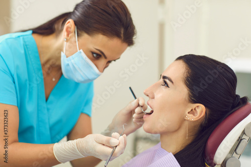 Dentist examining patients teeth with mirror in clinic  side view