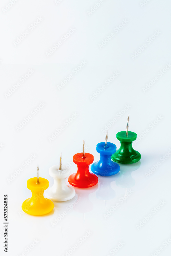 Multicolored push pins on white background. Close-up.