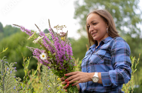 Beautiful middle age woman looking at wild flower bouquet harvested from nature.