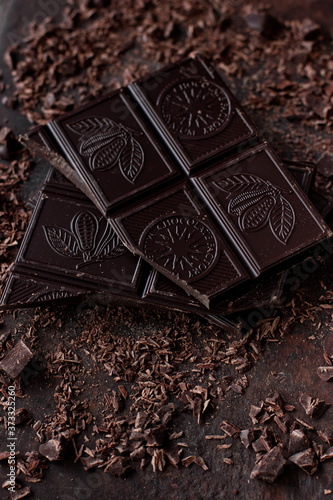 Broken dark chocolate bar on brown background. Closeup view