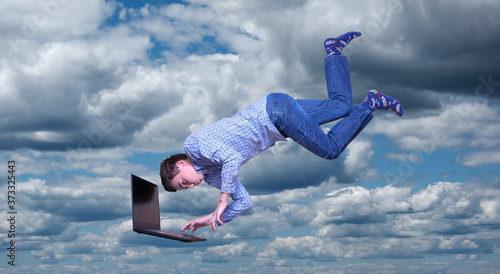 young man with laptop flies in the sky
