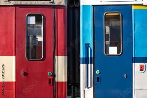 Closed Side Door of a Passenger Train Waiting on the Train Platform, Red and Blue Passage Car
