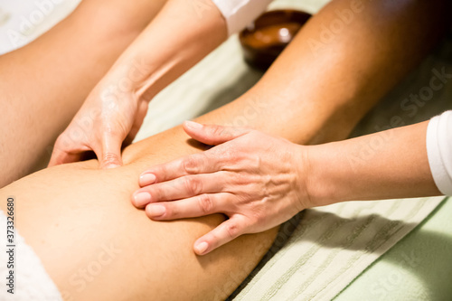 Masseuse woman hands giving a leg massage, finding a contracture, trigger point, a tight part in the muscle