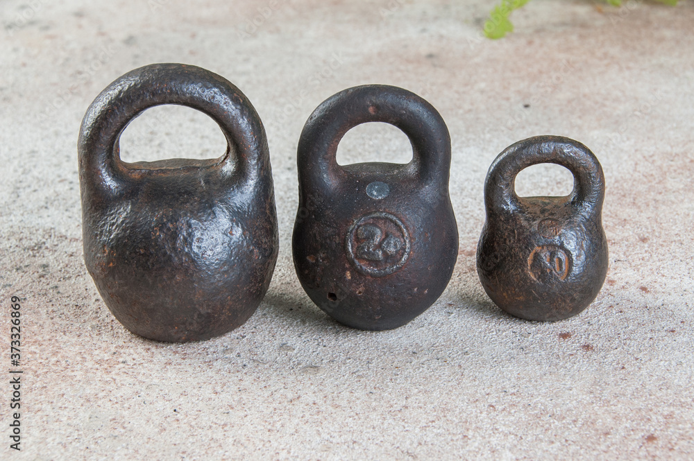 Three antique iron weights for scales on concrete background. Three antique iron weights for scales on concrete background.