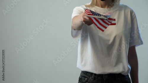 Blonde girl in face mask with USA flag and money on white background photo