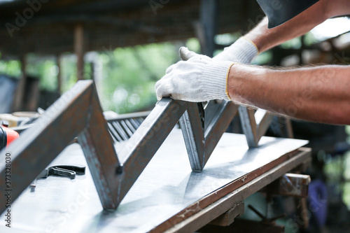 manual production of metal stairs. hands of a worker are making metal bowstring for stairs in a workshop close up outdoor