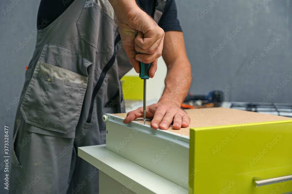 furniture assembly service worker assembles a kitchen cabinet with drawers. furniture assembly service worker assembles a kitchen cabinet with drawers.