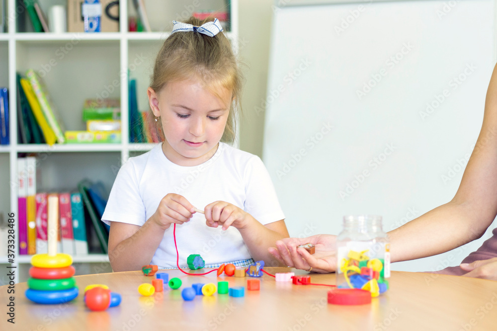 developmental and speech therapy classes with a child-girl. Speech therapy exercises and games with beads. The girl has beads in her hands developmental and speech therapy classes with a child-girl. Speech therapy exercises and games with beads. The girl has beads in her hands