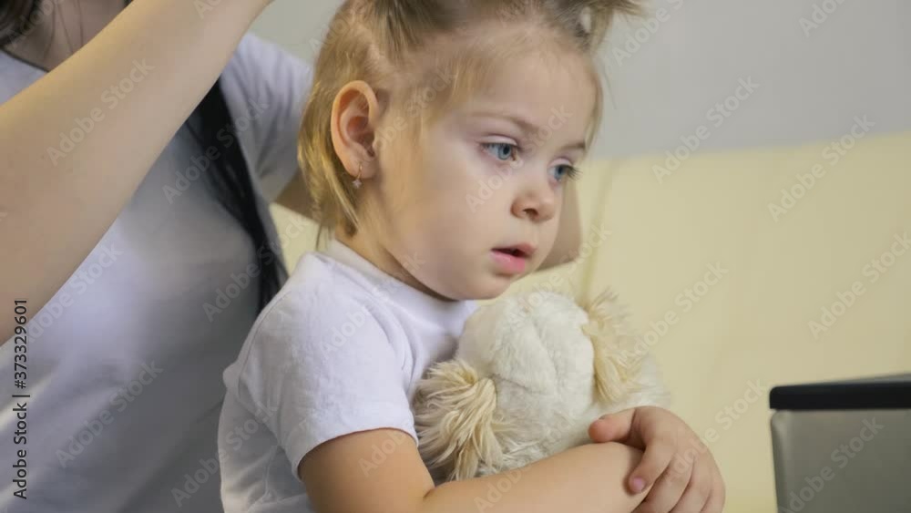 A caring young mother combs clean hair for her child. The girl makes a beautiful hairstyle for the baby. A caring young mother combs clean hair for her child. The girl makes a beautiful hairstyle for the baby.