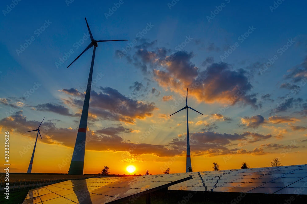 wind turbines and modern solar panels in the rural landscape at sunset