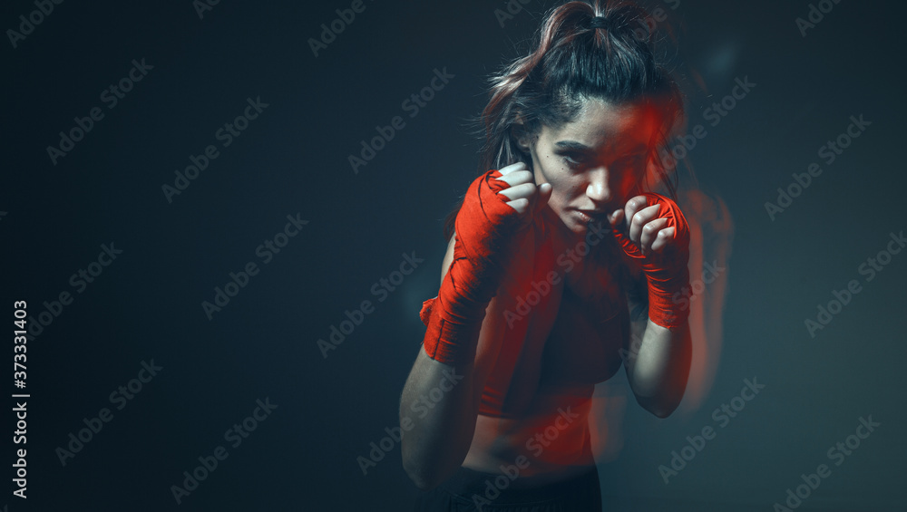 Beautiful female fighter trains in boxing bandages in studio on gray background. Women's mixed martial arts poster