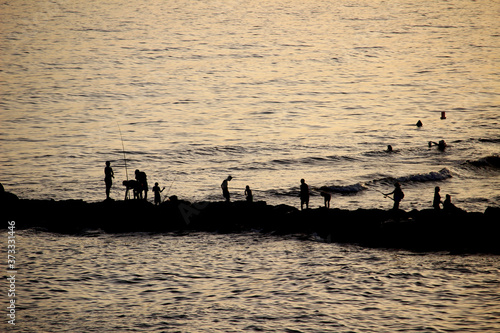 Fishermen fishing on a pier backlit