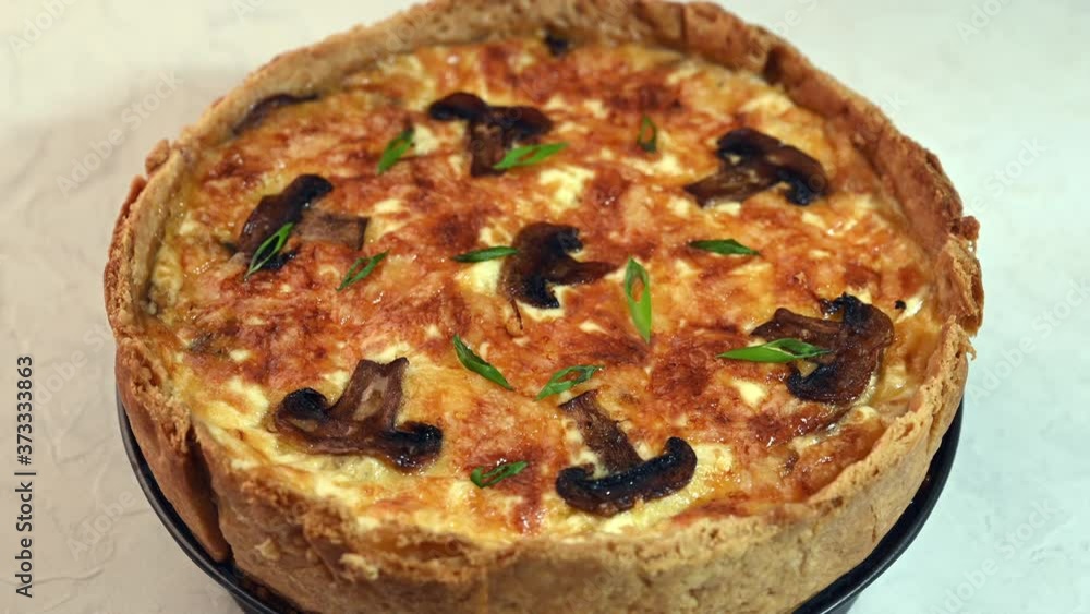 Traditional French pie quiche with mushrooms, cheese and onion slow rotates on the stand, selective focus, close up Traditional French pie quiche with mushrooms, cheese and onion slow rotates on the stand, selective focus, close up