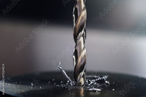 metal drill bit make holes in steel billet on industrial drilling machine. Metal work industry. multi cutting tool and end mill. photo