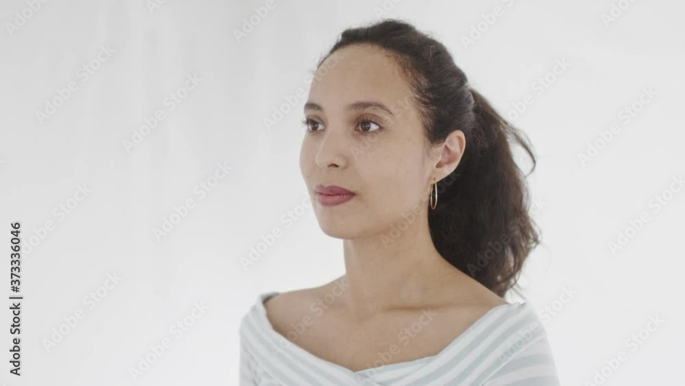 4K portrait of confident young pretty woman with ponytail and hoop earrings dressed in white striped top standing and looking ahead. 360 degree tracking arc shot movement. 4K portrait of confident young pretty woman with ponytail and hoop earrings dressed in white striped top standing and looking ahead. 360 degree tracking arc shot movement.
