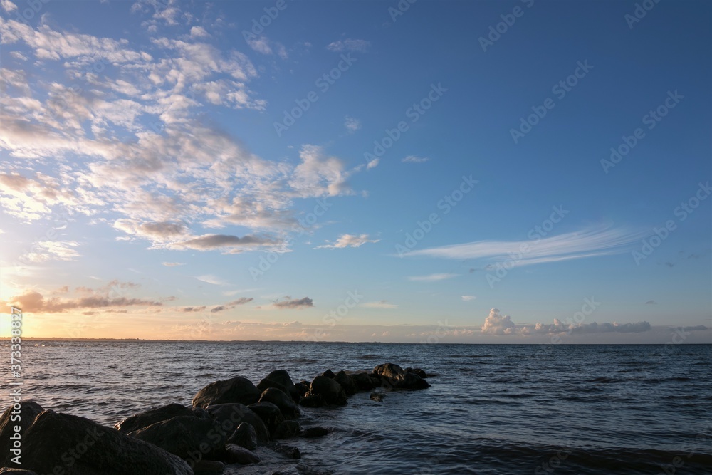 sea view with beautiful sidelight and rocks in the foreground