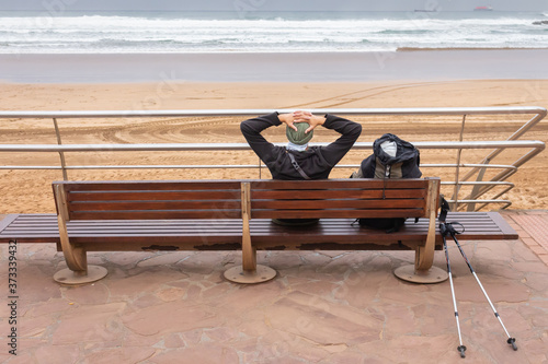 Konstfotografi Lonely tourist have a rest on wooden bench on the seaside
