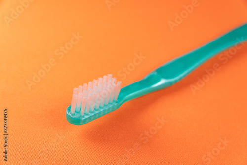 Green toothbrush on the orange background