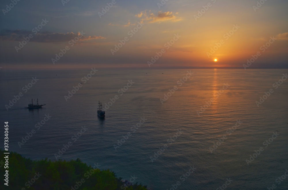 Sunset fantasy sailboat with the silhouette of a boat sailing on its journey against the background of a bright colorful sunset against a background of orange and yellow filled with sky. Sunset fantasy sailboat with the silhouette of a boat sailing on its journey against the background of a bright colorful sunset against a background of orange and yellow filled with sky.