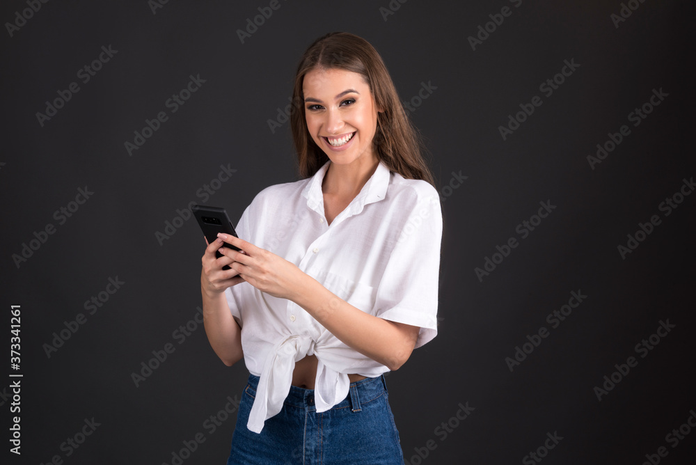 young woman holding smart phone isolated on dark background young woman holding smart phone isolated on dark background