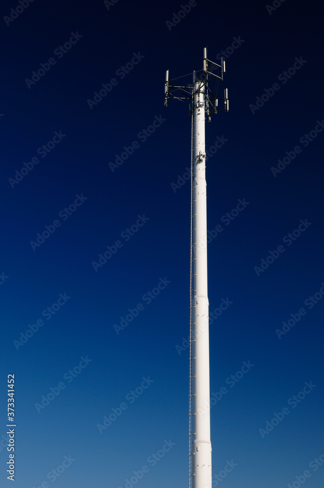 White steel cell phone communications tower against a dark blue sky White steel cell phone communications tower against a dark blue sky