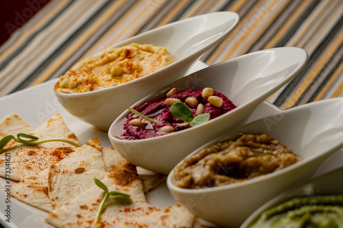 Colorful hummus bowls, healthy vegan dips. Traditional Middle eastern hummus, green hummus, beetroot hummus, spread. Assorted meze and dips with pita bread. Meze and snacks set, copy space.
