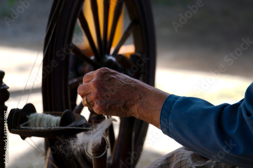 Old lady spinning yarn on spinning-wheel
