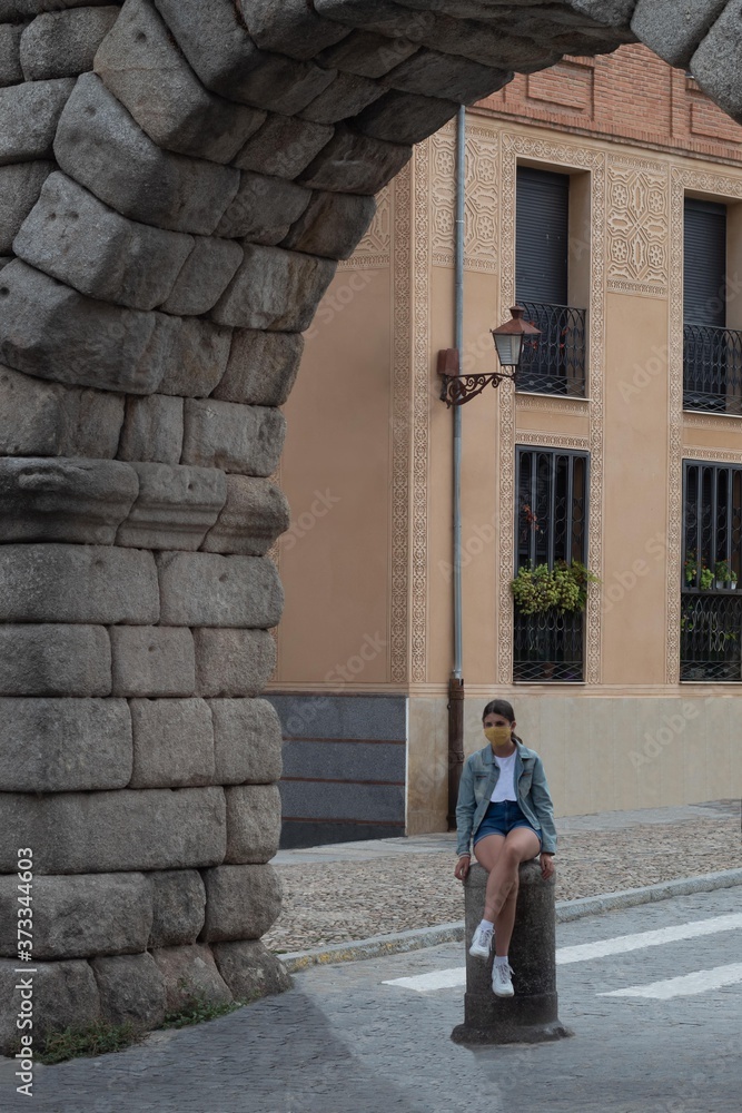 girl sitting on a stone column under an ancient arch in a Roman city
