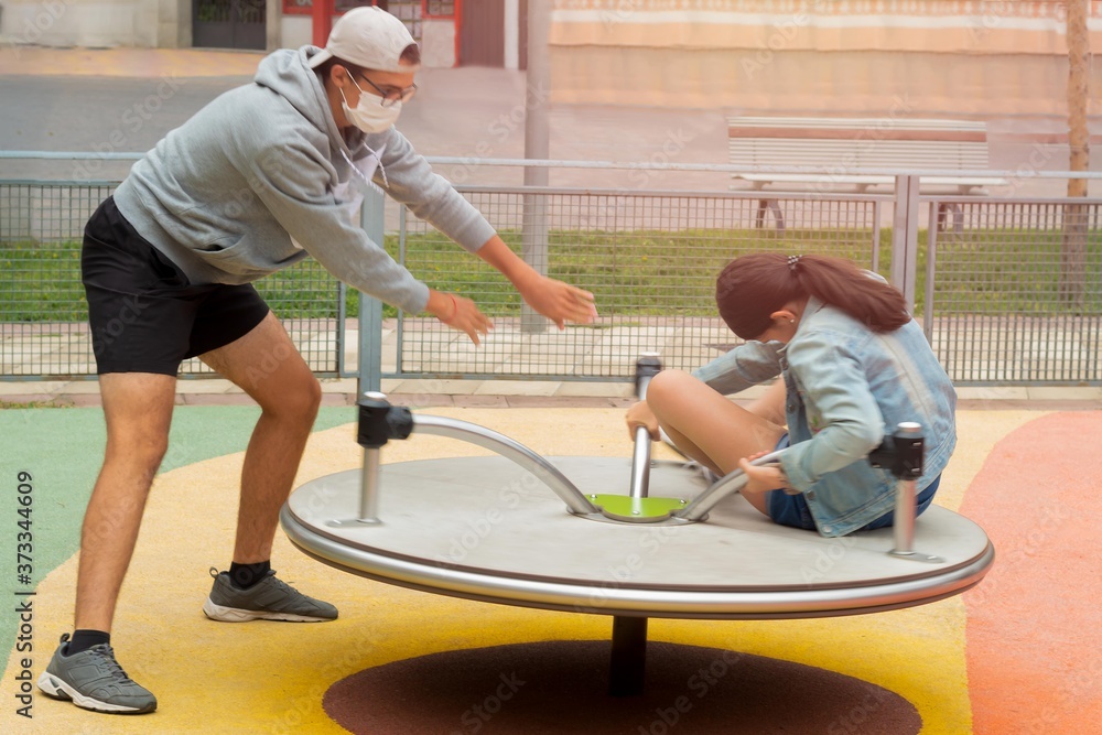 young man spinning his sister on the swing and enjoying Covid19 time with a mask young man spinning his sister on the swing and enjoying Covid19 time with a mask