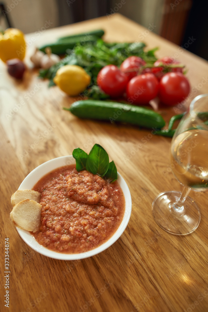 Close up of bowl of tomato soup or Pappa al Pomodoro served with a glass of white wine. The soup with tomatoes and bread, traditional Italian Tuscan dish Close up of bowl of tomato soup or Pappa al Pomodoro served with a glass of white wine. The soup with tomatoes and bread, traditional Italian Tuscan dish