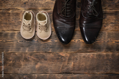 Baby and father shoes on the wooden floor flat lay background with copy space.