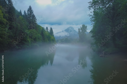 Scary spooky river of Kolpa on a gray dull summer day with clouds and overcast sky with thick fog above the water surface. Scary river scene