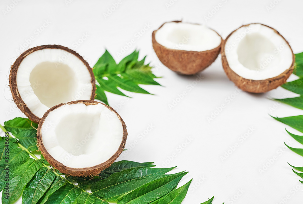 Flat lay coconut with half and leaves on white background. Hello summer! Green and white color. Copy space. Tropical nut coconut. Vegetarian, vegan, raw food, tropical fruits. Healthy food and diet Flat lay coconut with half and leaves on white background. Hello summer! Green and white color. Copy space. Tropical nut coconut. Vegetarian, vegan, raw food, tropical fruits. Healthy food and diet