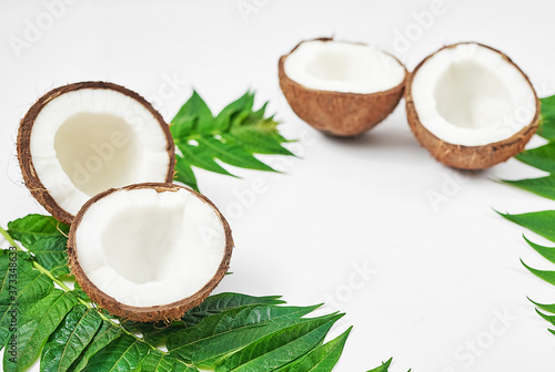 Flat lay coconut with half and leaves on white background. Hello summer! Green and white color. Copy space. Tropical nut coconut. Vegetarian, vegan, raw food, tropical fruits. Healthy food and diet