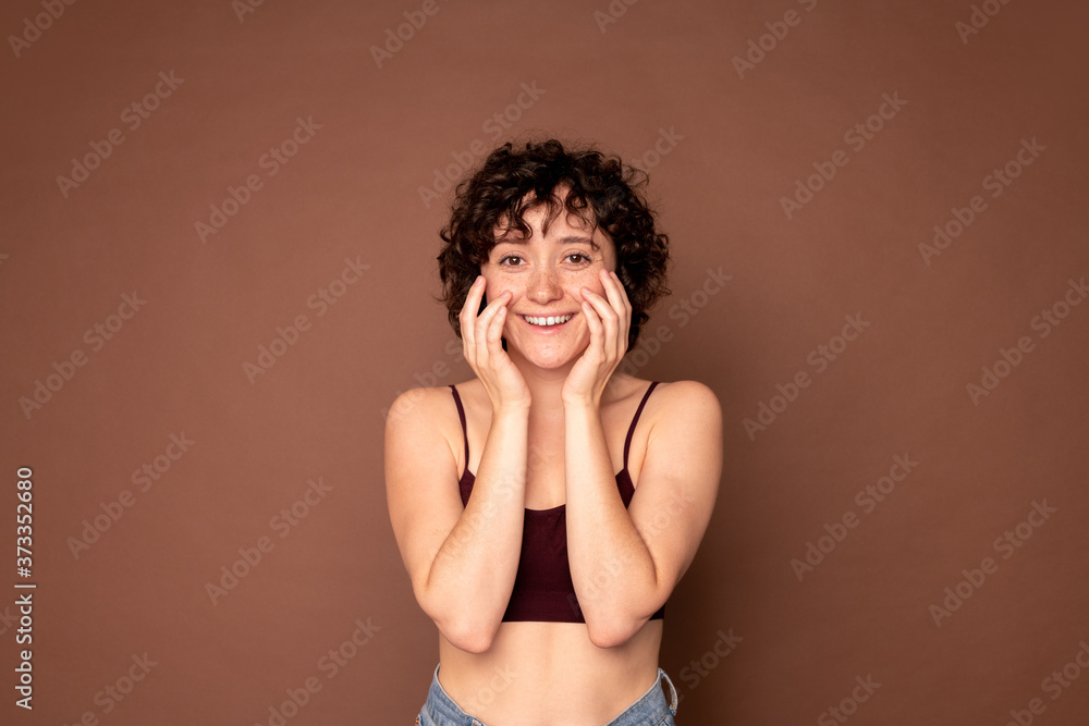 Happy young beautiful woman with short dark curly hair keeping her hands by face Happy young beautiful woman with short dark curly hair keeping her hands by face