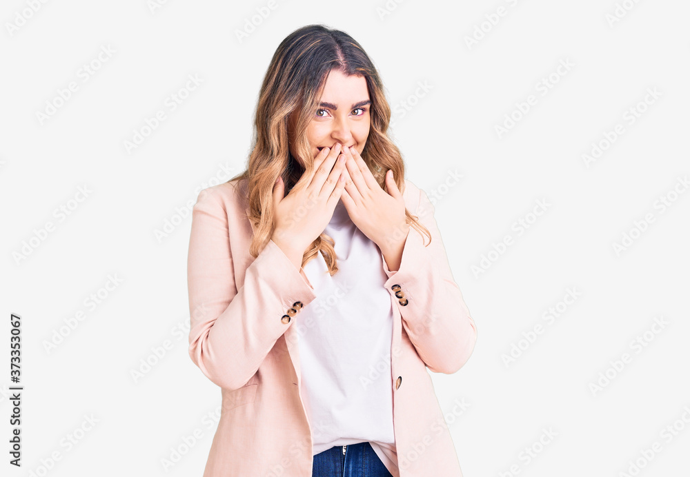 Young caucasian woman wearing business clothes laughing and embarrassed giggle covering mouth with hands, gossip and scandal concept