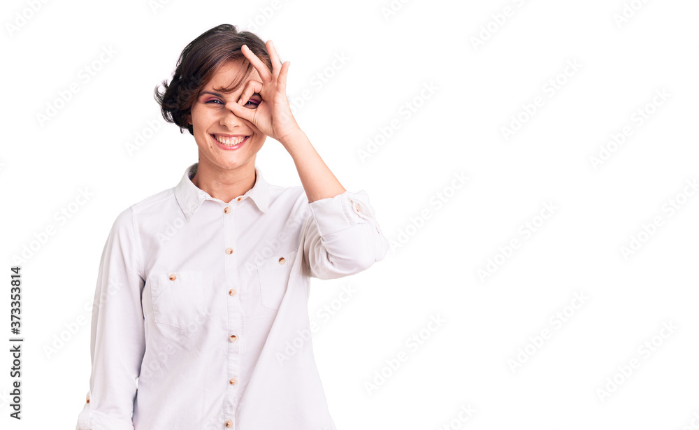 Beautiful young woman with short hair wearing elegant white shirt doing ok gesture with hand smiling, eye looking through fingers with happy face. Beautiful young woman with short hair wearing elegant white shirt doing ok gesture with hand smiling, eye looking through fingers with happy face.