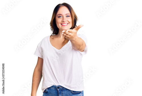 Young beautiful caucasian woman wearing casual white tshirt smiling friendly offering handshake as greeting and welcoming. successful business.