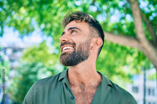 Young hispanic man smiling happy walking at the park