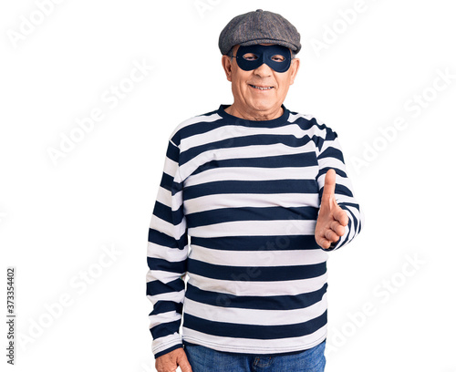 Senior handsome man wearing burglar mask and t-shirt smiling cheerful offering palm hand giving assistance and acceptance Fototapet