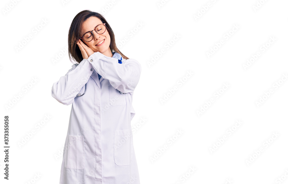 Young beautiful woman wearing doctor stethoscope and glasses sleeping tired dreaming and posing with hands together while smiling with closed eyes. Young beautiful woman wearing doctor stethoscope and glasses sleeping tired dreaming and posing with hands together while smiling with closed eyes.