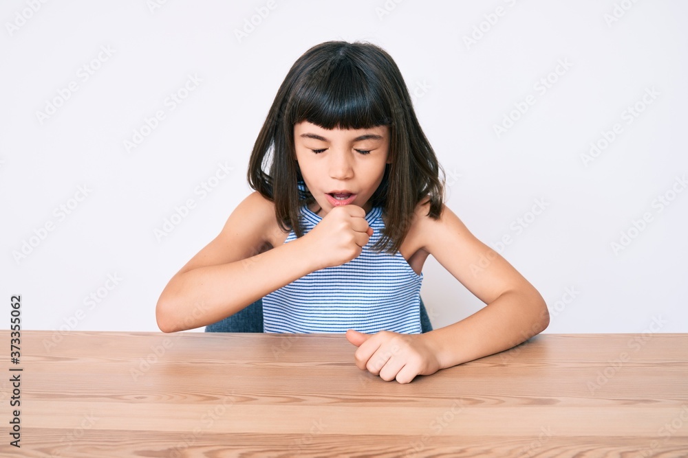 Young little girl with bang wearing casual clothes sitting on the table feeling unwell and coughing as symptom for cold or bronchitis. health care concept. Young little girl with bang wearing casual clothes sitting on the table feeling unwell and coughing as symptom for cold or bronchitis. health care concept.