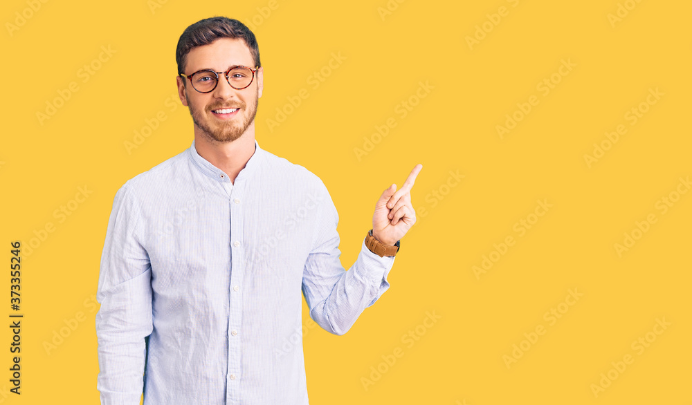 Handsome young man with bear wearing elegant business shirt and glasses with a big smile on face, pointing with hand finger to the side looking at the camera. Handsome young man with bear wearing elegant business shirt and glasses with a big smile on face, pointing with hand finger to the side looking at the camera.