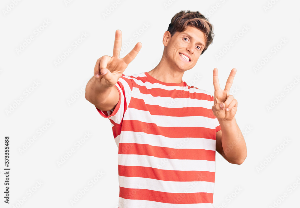 Young handsome man wearing casual clothes smiling looking to the camera showing fingers doing victory sign. number two. Young handsome man wearing casual clothes smiling looking to the camera showing fingers doing victory sign. number two.