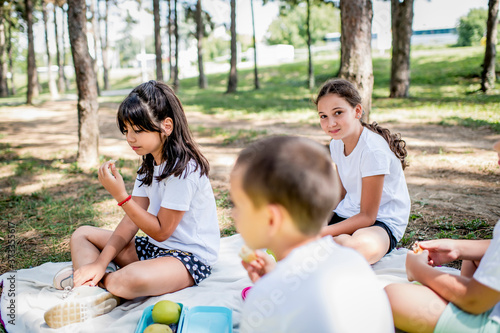 School children in white t shirt eating lunch during their lunch break at school