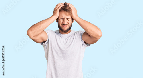 Fotografia Young caucasian man wearing casual white tshirt suffering from headache desperate and stressed because pain and migraine