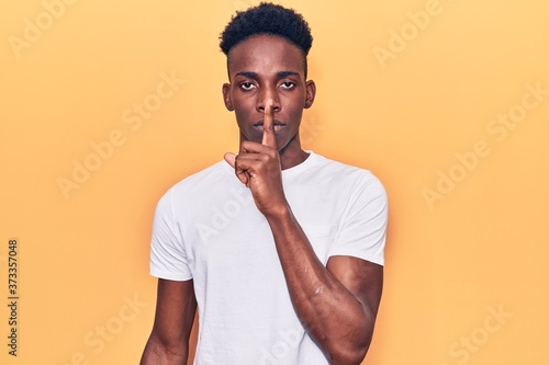 Young african american man wearing casual clothes asking to be quiet with finger on lips. silence and secret concept.