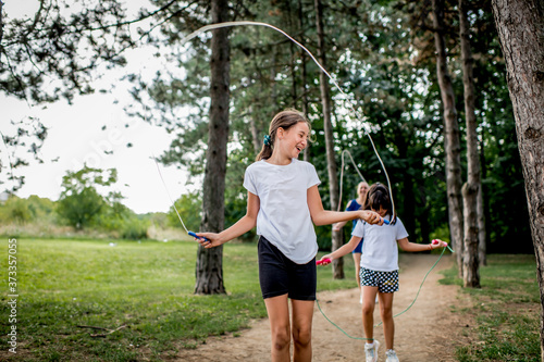 School children in white t shirts skipping ropes at public park