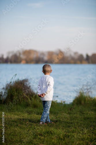 .A girl with a short haircut in a white knitted sweater looks towards the lake © галина шарапова